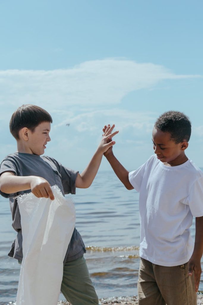 Two diverse children cleaning up the seaside, promoting environmental volunteerism and teamwork.